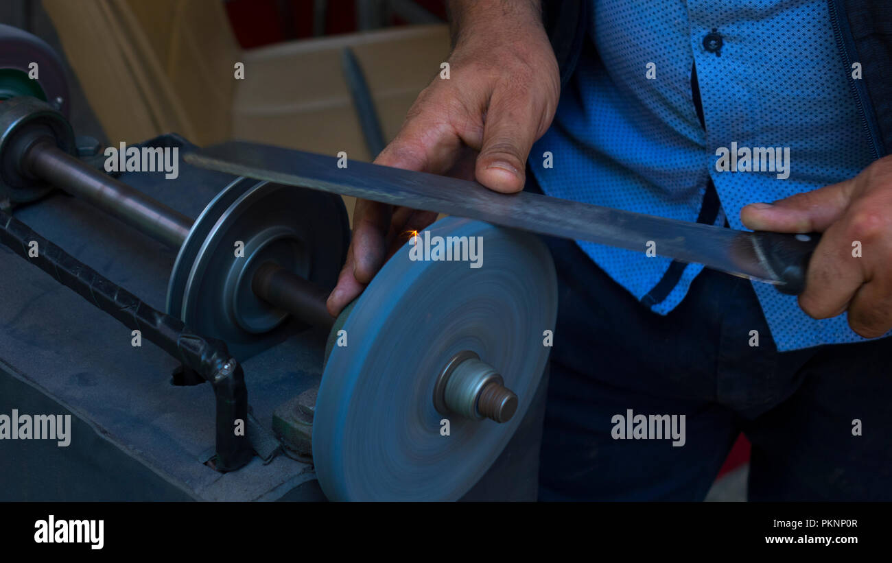 Man grinding on abrasive cutting and knife-sharpening stones Stock Photo