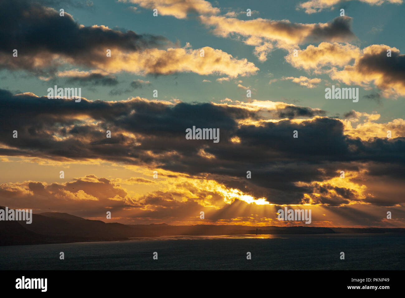 Sunburst through clouds over the North Wales coast at sunset Stock Photo