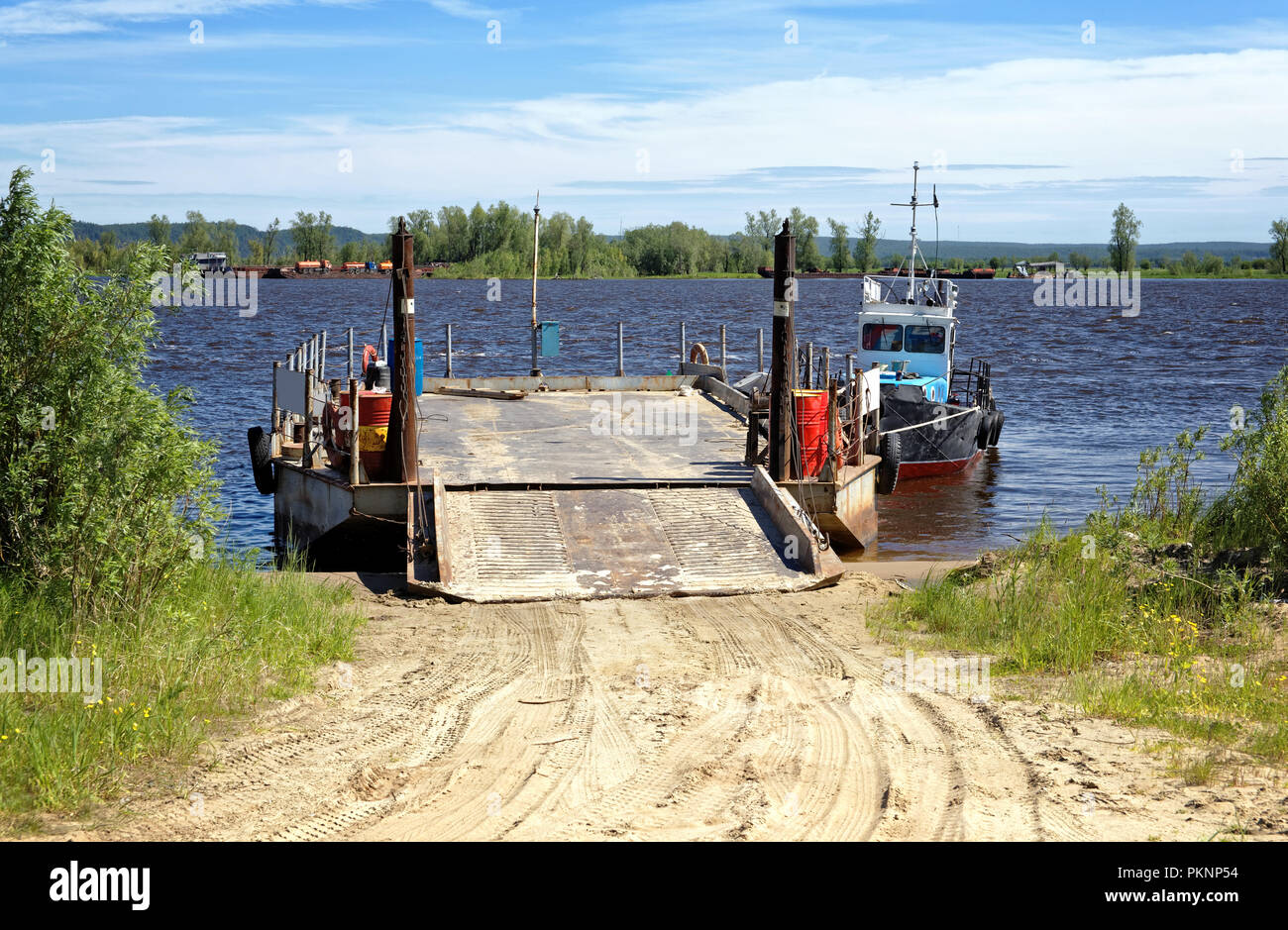Empty river barge with ramp and boat on the pier. Delivery of goods and ...