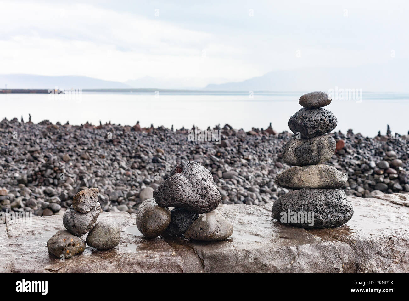 Zen-like cairns built from lava rock by tourists on the waterfront at Reykjavik, looking across Faxa Bay to the Snaefellsnes Peninsula, Iceland Stock Photo