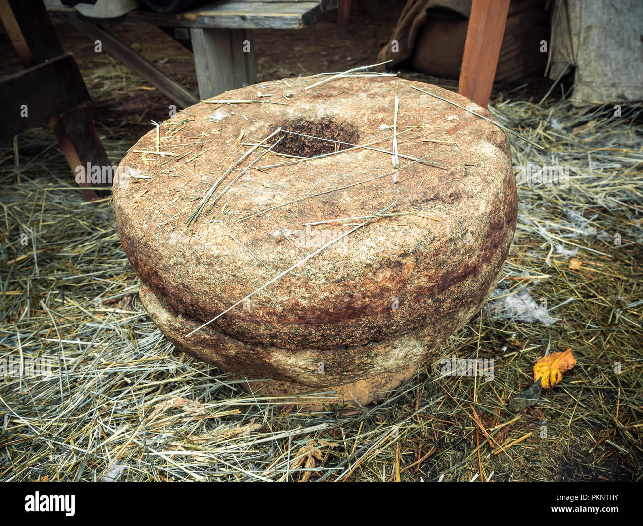 The ancient Quern stone hand mill with grain. . Old grinding stones