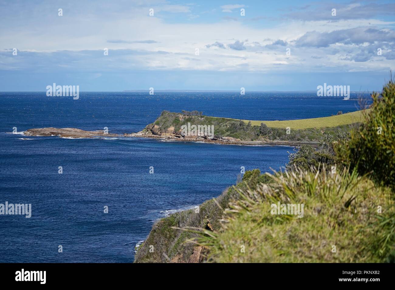 Coastal view of a headland, in the middle distance, from a higher vantage point. The horizon in the distance. Stock Photo