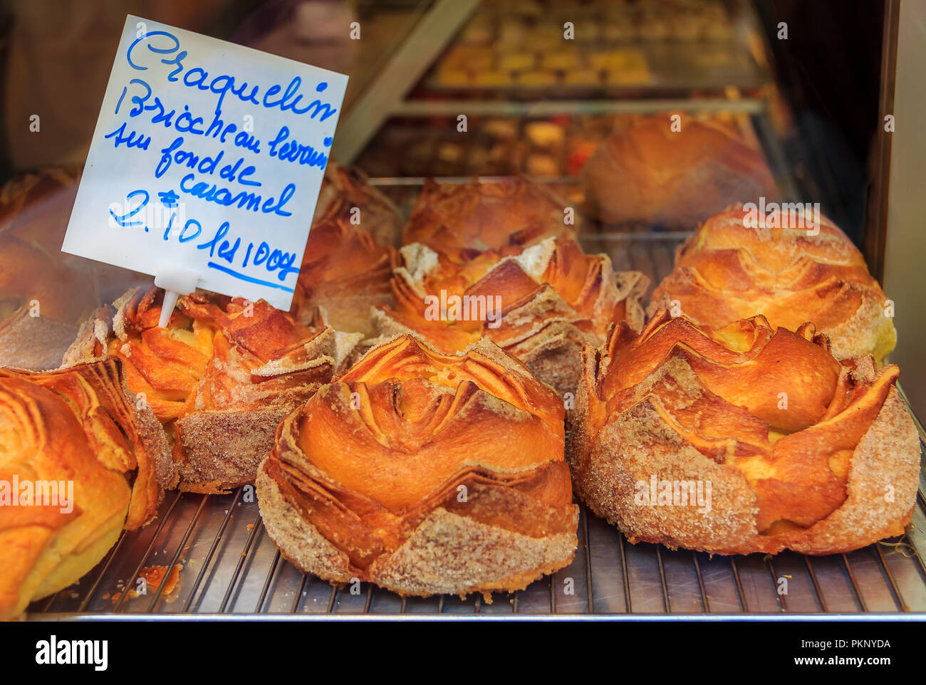 Ornate French craquelin, sugary brioche with a crispy top and caramel filling on display at a bakery in Cannes, France Stock Photo