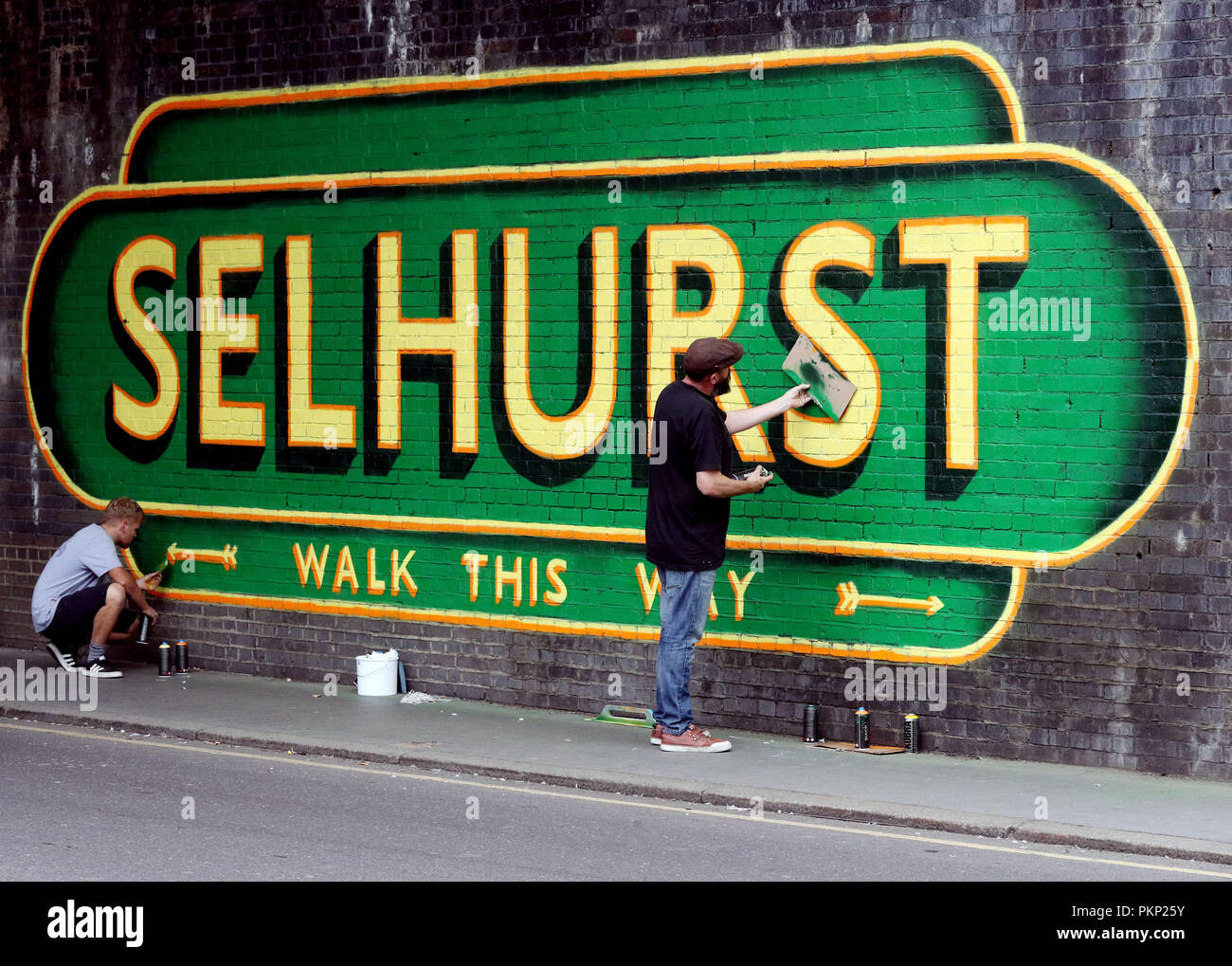 Artist Lionel Stanhope (right) working underneath a railway bridge 