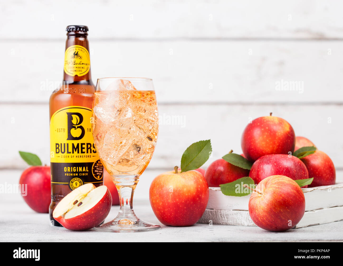 LONDON, UK - SEPTEMBER 13, 2018: Bottle of Bulmers Original Cider and glass of ice cubes with fresh apples on wood background. Stock Photo