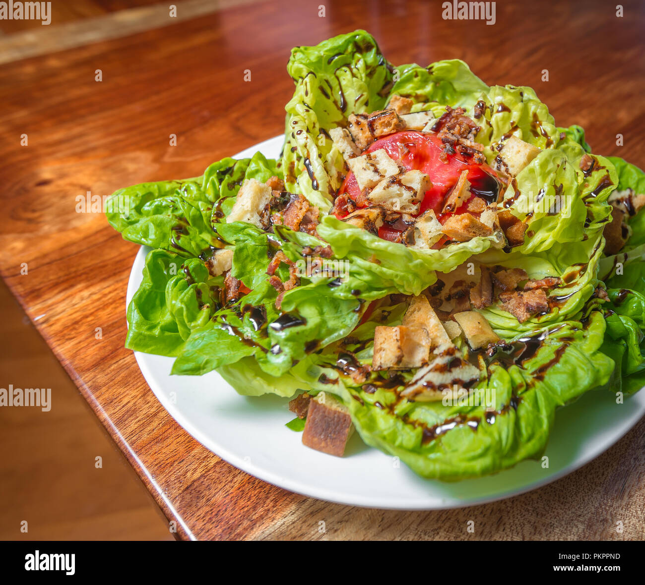A BLT salad with bacon, tomatoes, and croutons on a wooden table Stock Photo