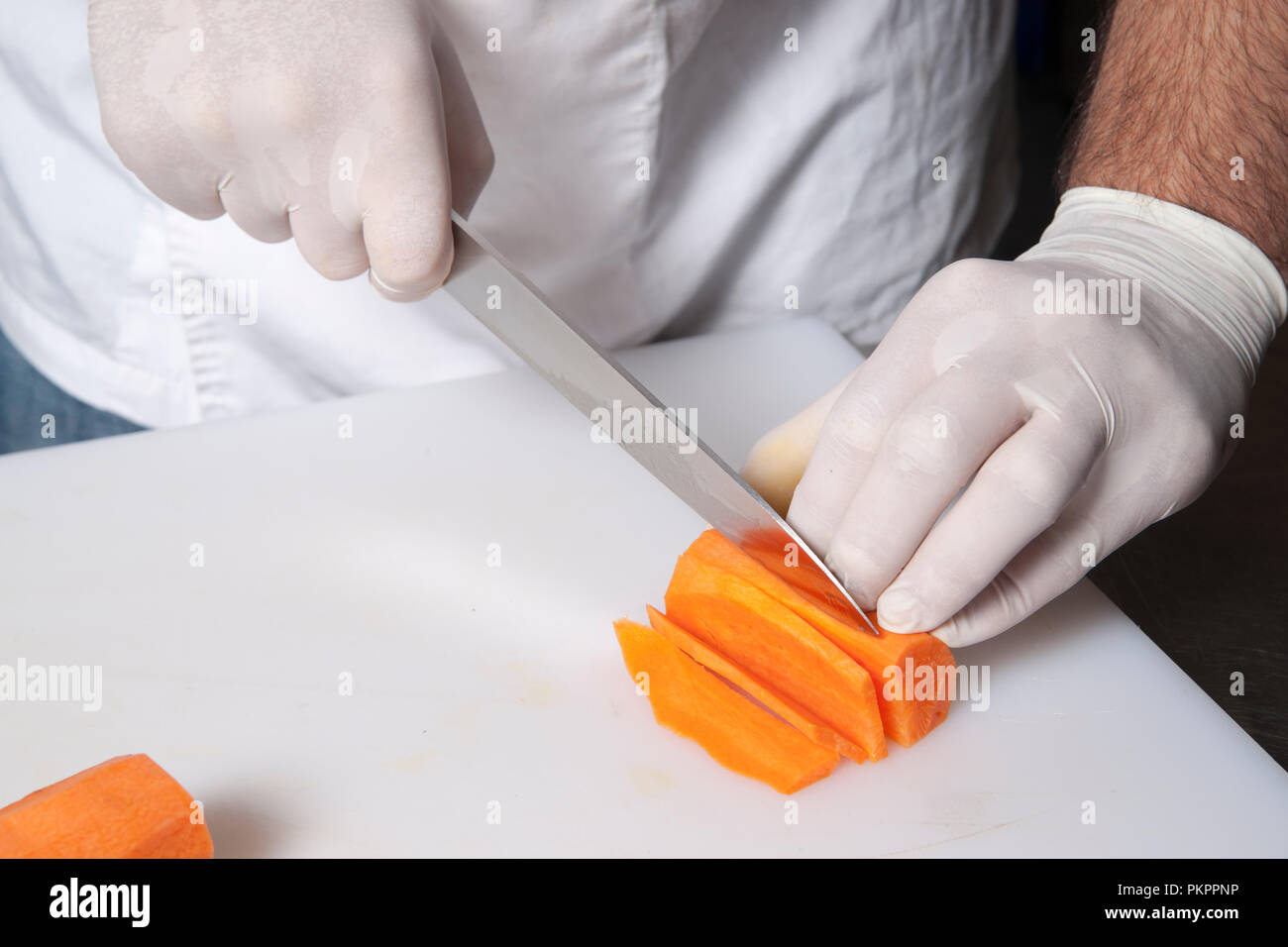 the chef in gloves cuts carrots Stock Photo