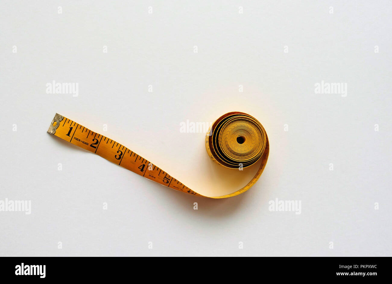 Yellow fiberglass tape measure on a white background. Stock Photo