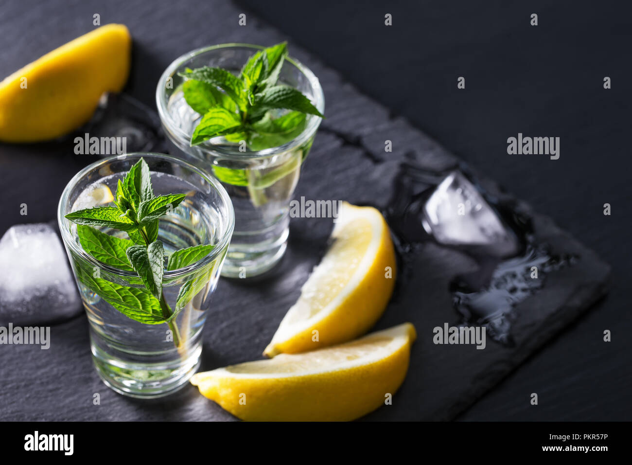 Gin or vodka with mint lemon and ice on a black background. Alcohol cocktail with citrus and