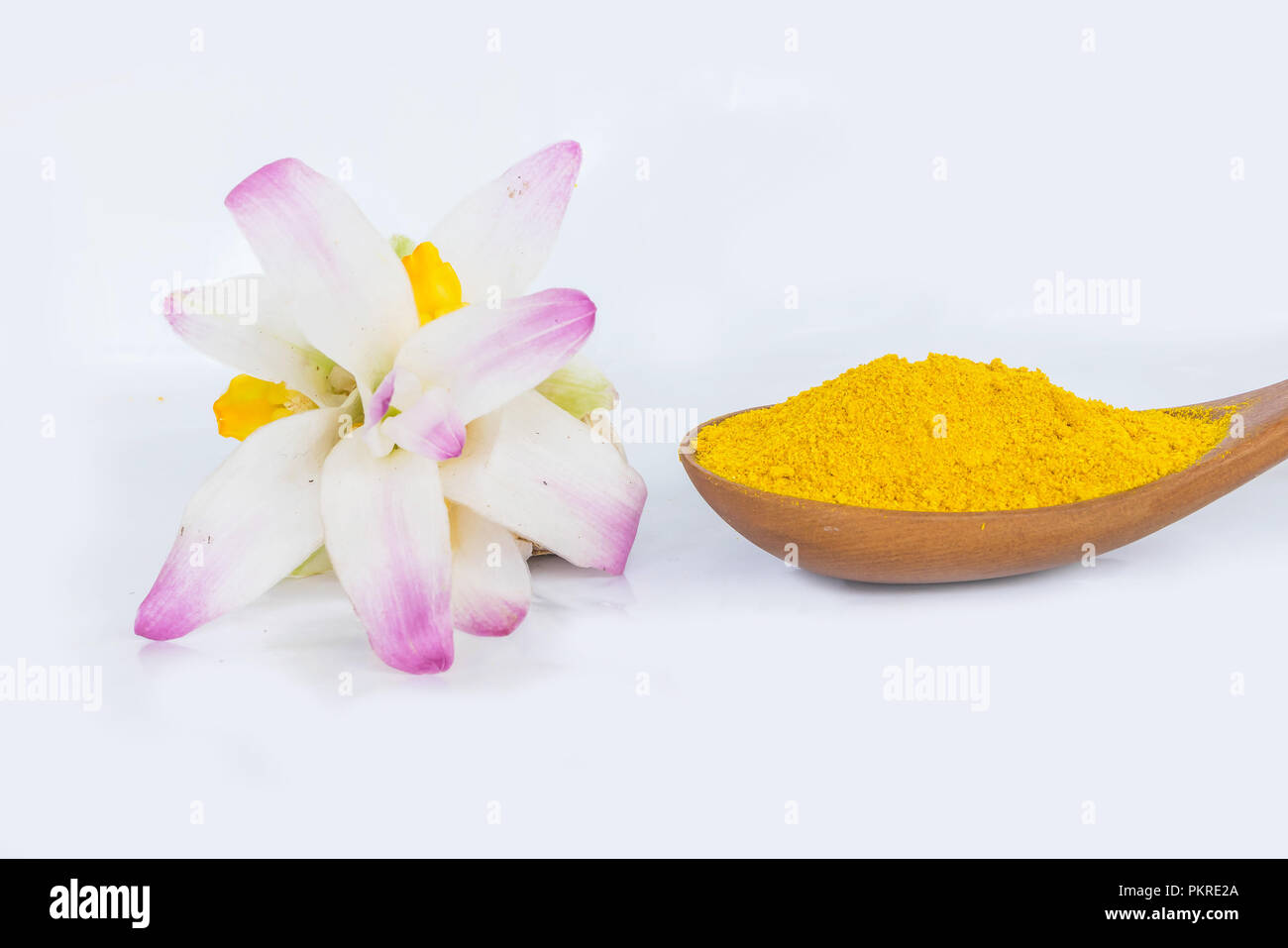 Turmeric powder on the wooden spoon, Zingiber,Turmeric root, Cassumunar ginger, Bengal root,Zingiberaceae,and tumeric flower on the white background.  Stock Photo