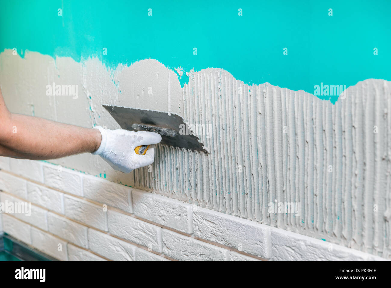 tiler applying tile adhesive on the wall Stock Photo