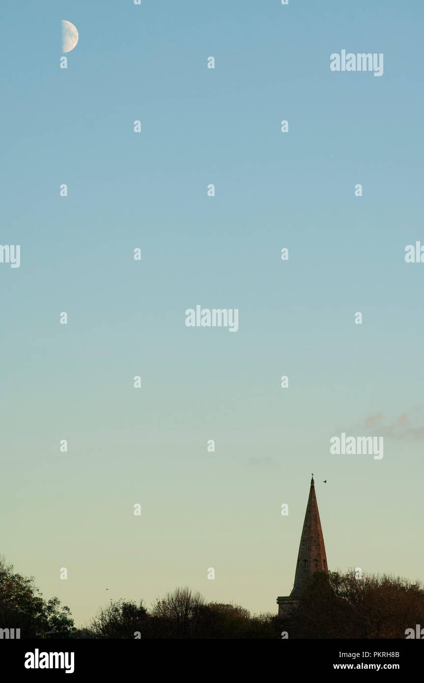 St.Hilary Church spire at sunset with a crescent moon in the top left ...