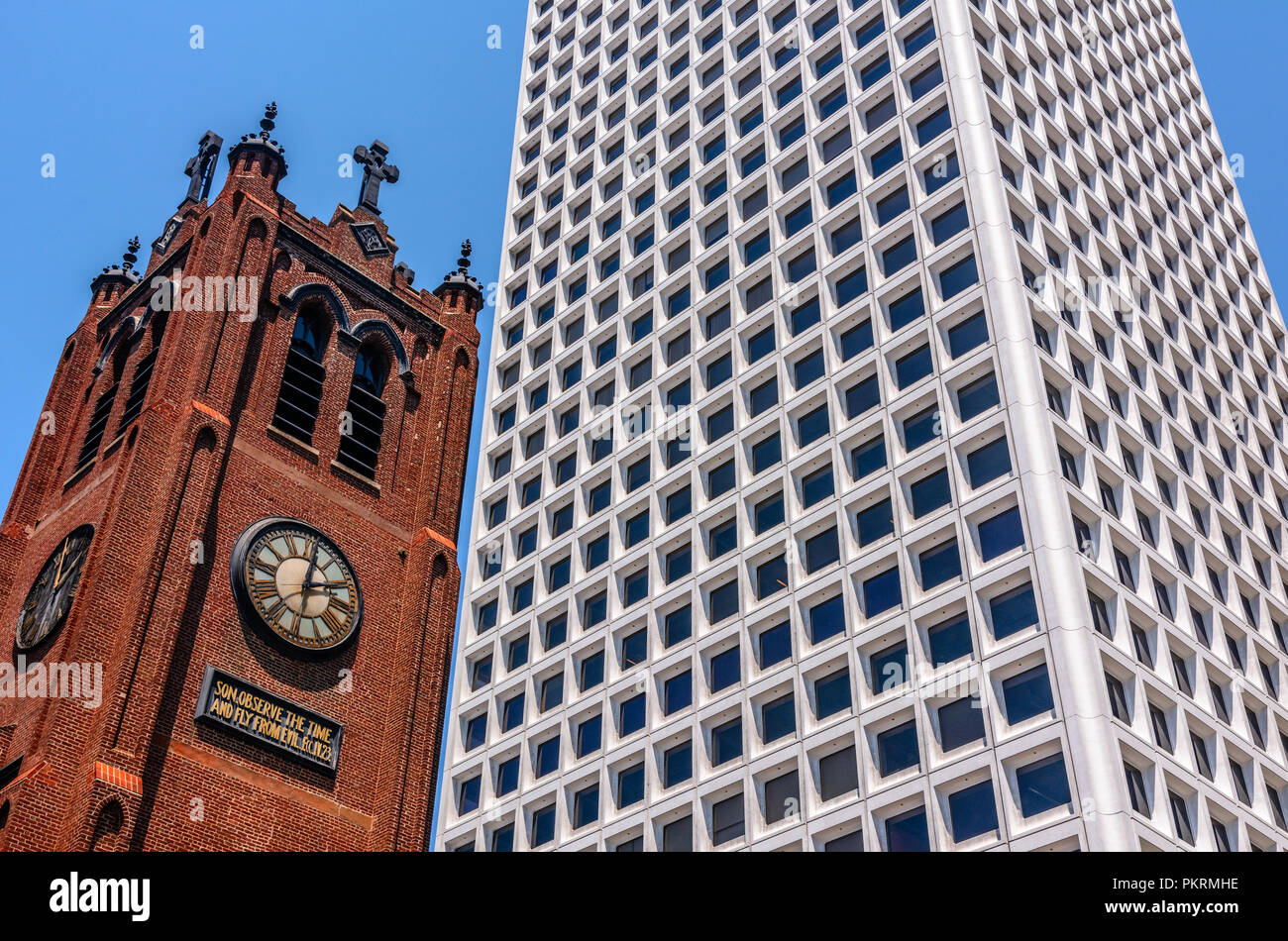 Old Brick Church With A Clock On It Next To A Modern White Skyscraper Stock Photo
