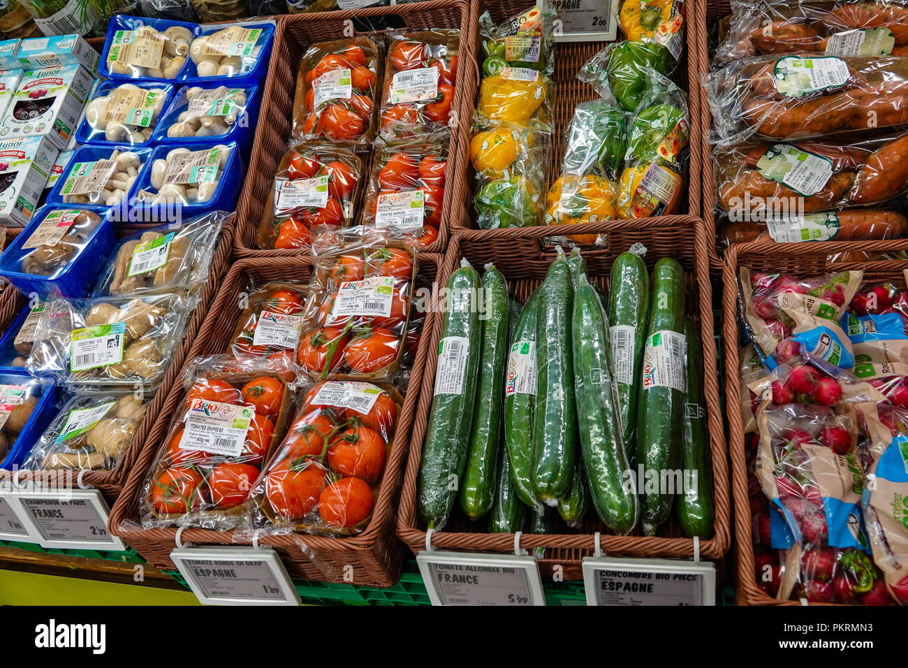 Vegetables wrapped in plastic in French supermarket with tomatoes, cucumber, peppers, Stock Photo