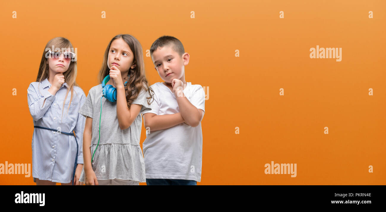 Group of boy and girls kids over orange background serious face thinking  about question, very confused idea Stock Photo - Alamy