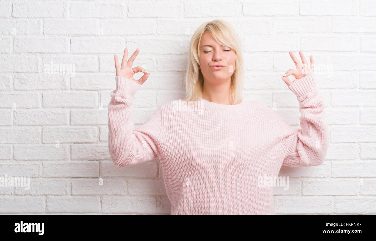 Adult caucasian woman over white brick wall wearing winter sweater ...