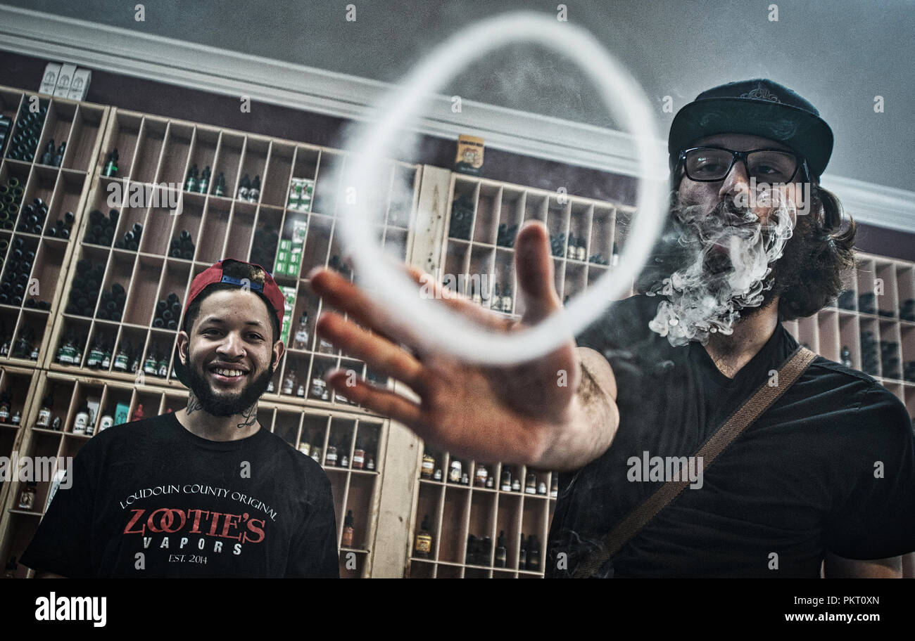 UNITED STATES - March 28, 2016: Trey Bush watches as Gabe Lukasiak blows a  vapor ring at Zootie's Vapors the new vaping store in Leesburg Virginia on  Stock Photo