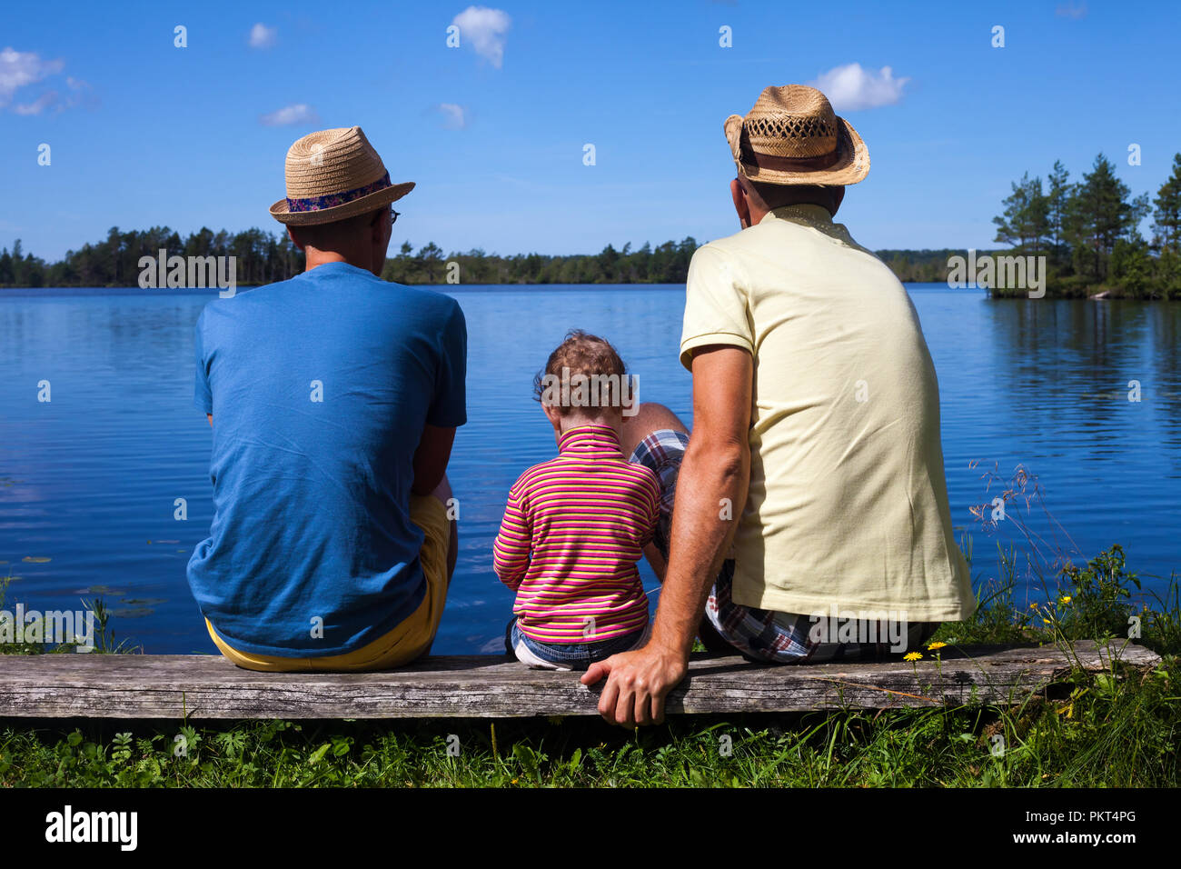 Two-father family with a redhead toddler at the lake Stock Photo