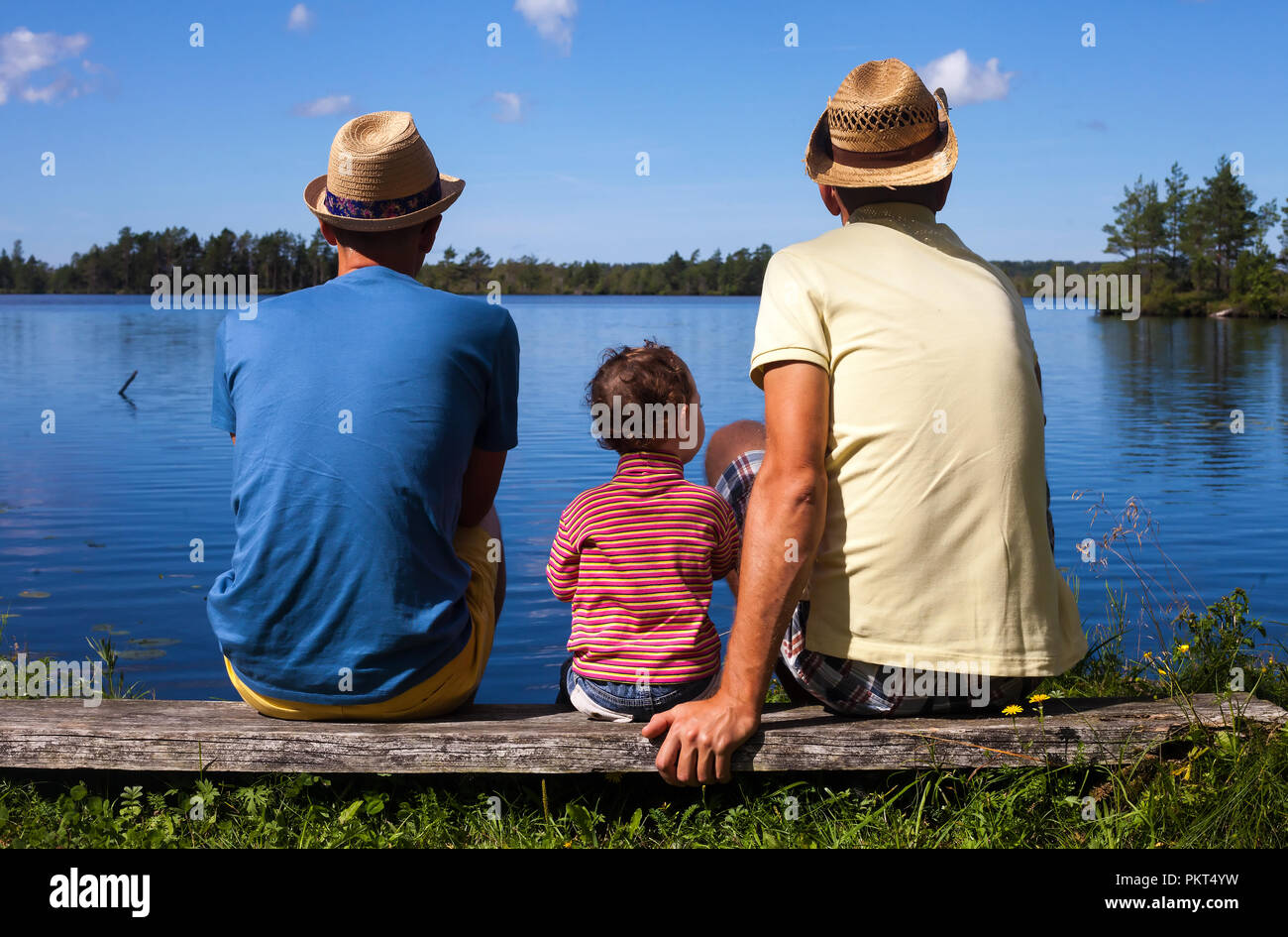 Two dads and a kid on a walk at a riverside Stock Photo