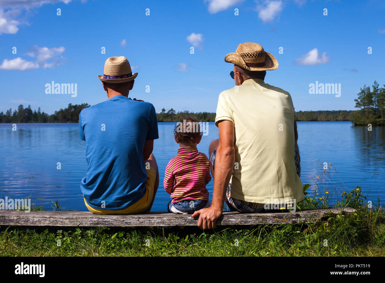 Two men and a toddler at a lake during nice summer day Stock Photo