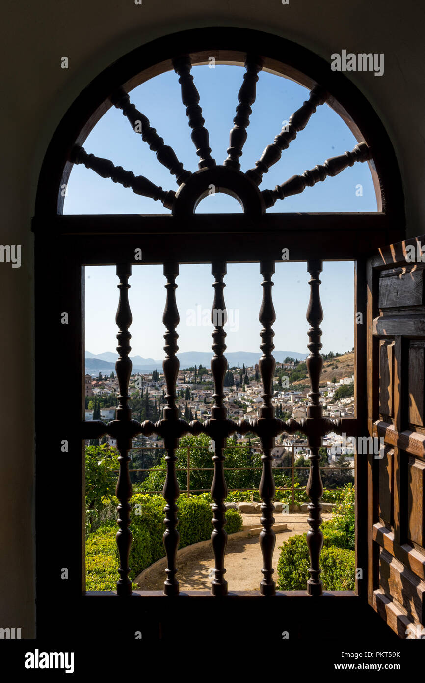 View of the Albayzin district of Granada, Spain, from an arched window grill in the Alhambra palace near sunset at Granada, Spain, Europe on a bright  Stock Photo