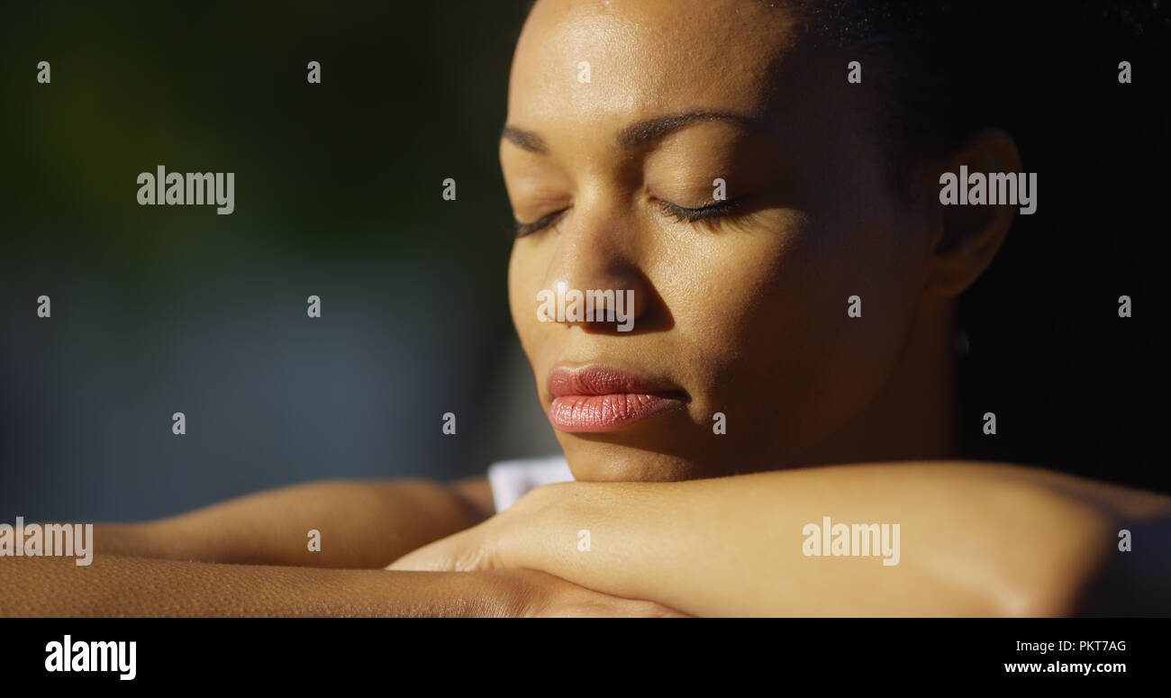 Black woman sitting with eyes closed outdoors Stock Photo - Alamy