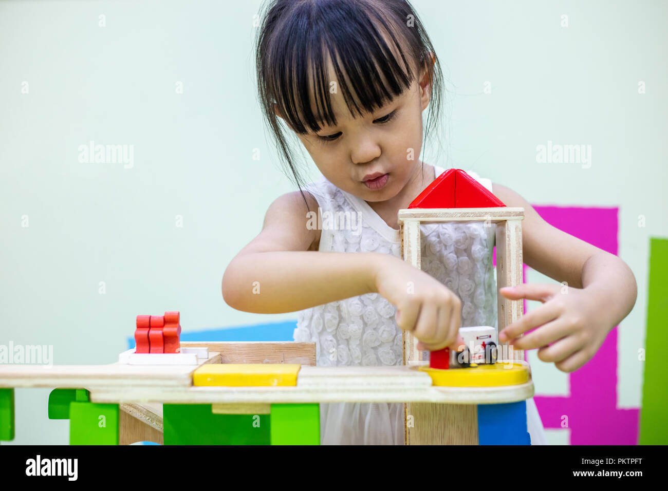 Asian Chinese little girl playing wooden toy train at indoor playground ...