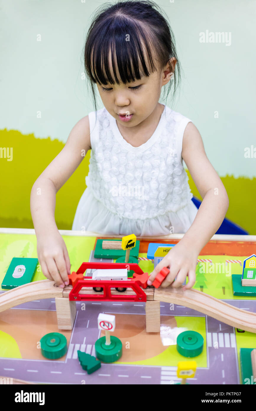 Asian Chinese little girl playing wooden toy train at indoor playground ...