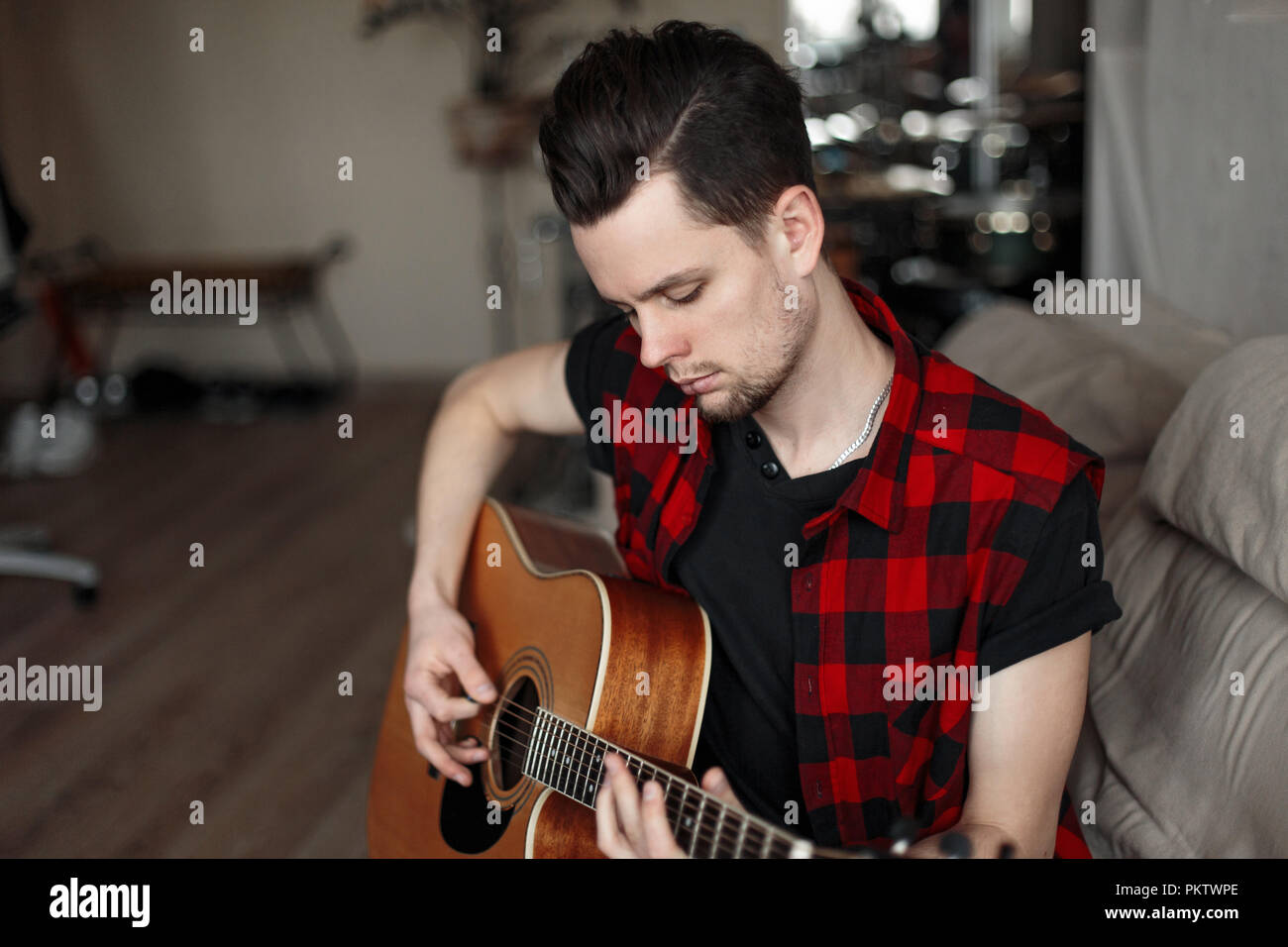 Young handsome man with guitar sitting on the couch Stock Photo