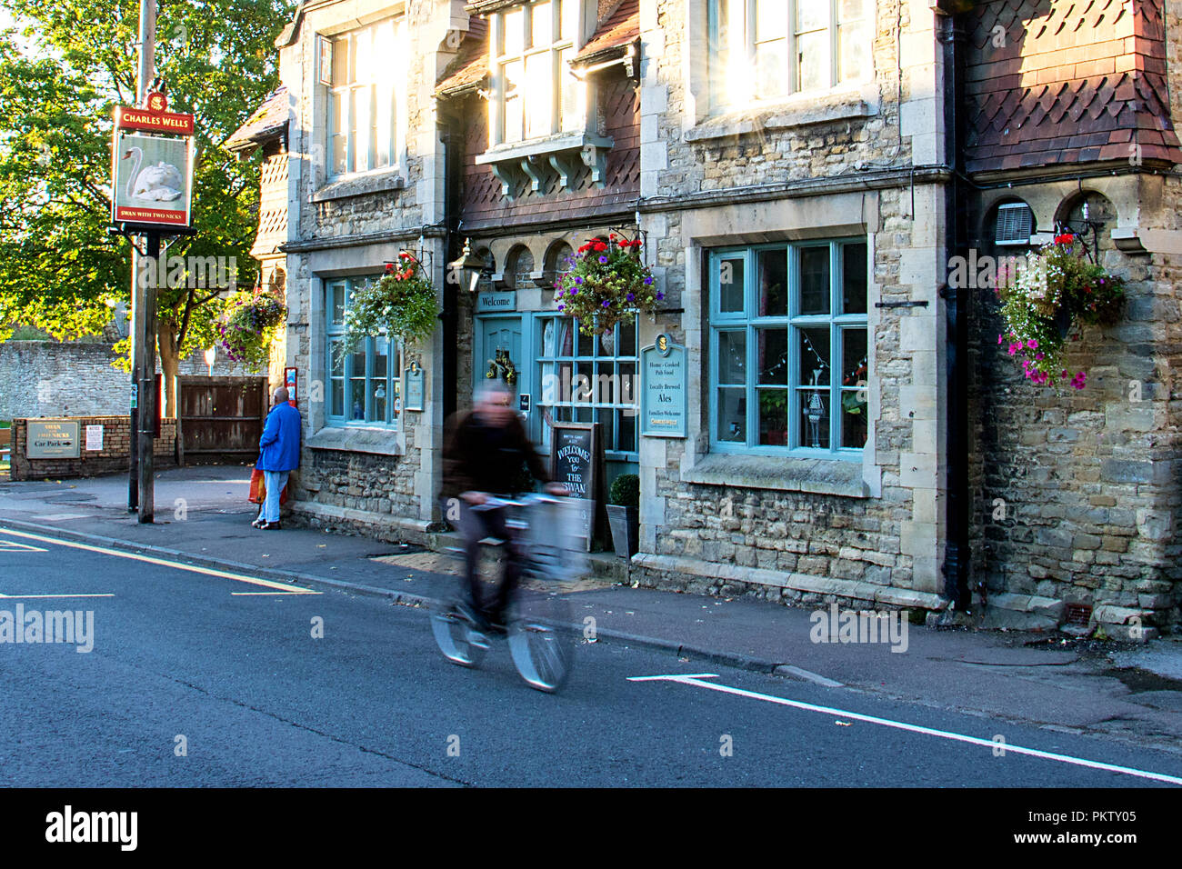 A cyclist passing an English country pub in the village of Sharnbrook, Bedfordshire, England Stock Photo