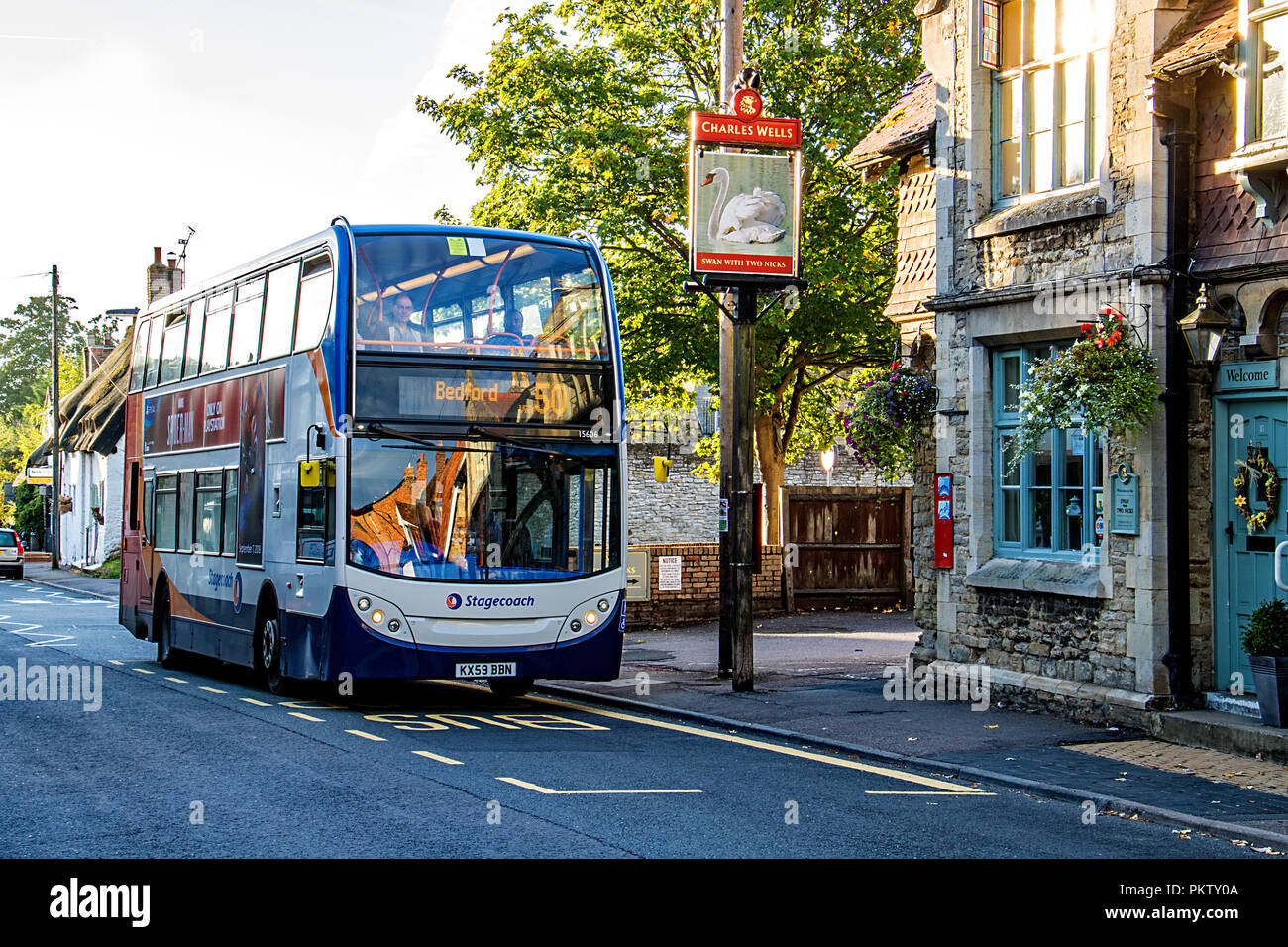 A bus waits for passengers at a bus stop outside an English country pub in the village of Sharnbrook, Bedfordshire, England Stock Photo