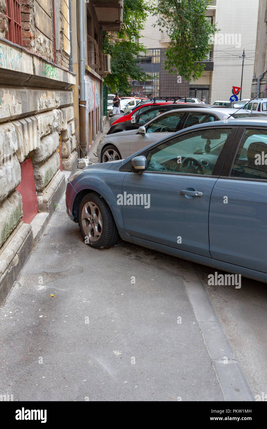 Typical pavement car parking in central Bucharest, Romania.  Parking on pavements, in driving lanes & blocking others is normal in Bucharest. Stock Photo