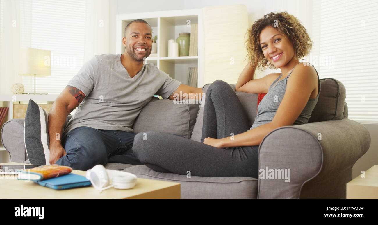 African couple sitting on couch smiling Stock Photo - Alamy