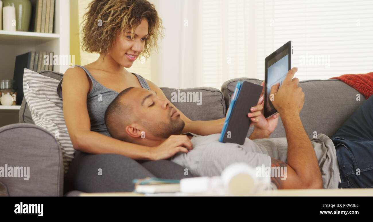 African couple using tablets on couch Stock Photo