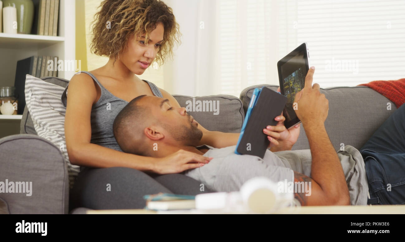 African couple using tablets on couch Stock Photo