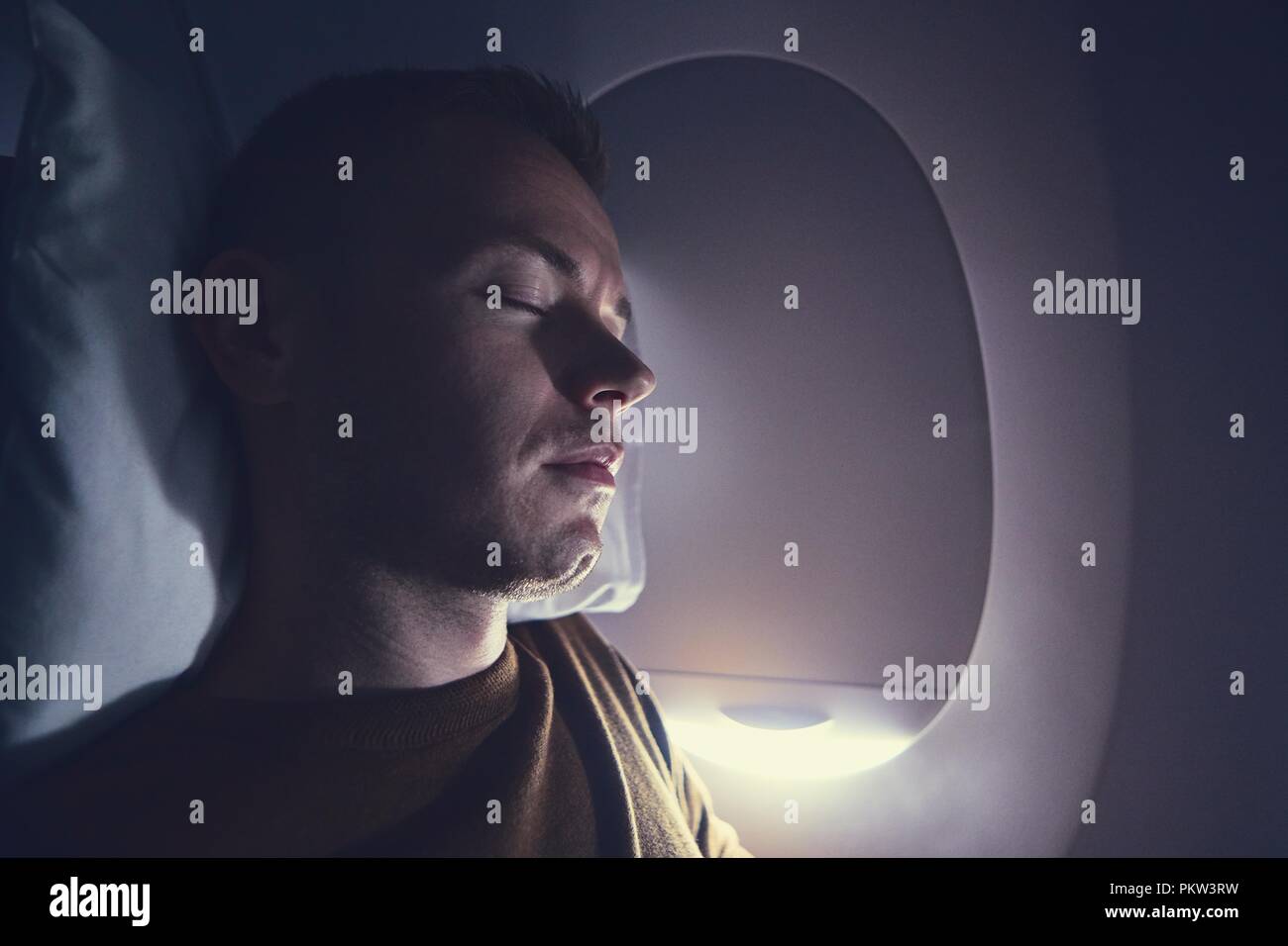 Traveling by airplane. Young passenger sleeping during flight. Stock Photo