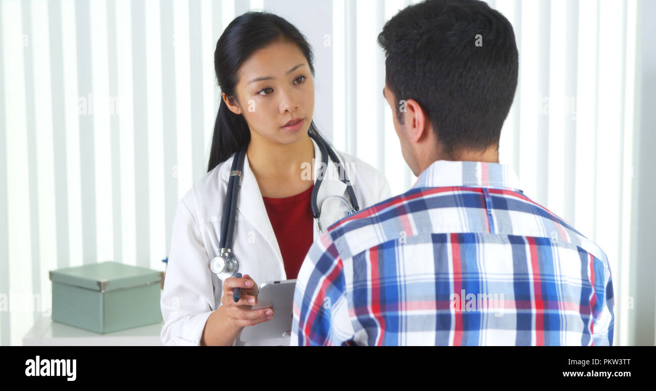 Asian doctor asking patient questions and taking notes Stock Photo Alamy