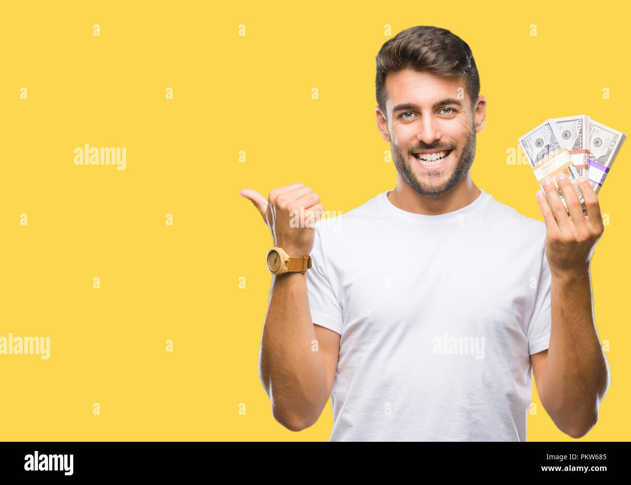 Young handsome man holding stack of dollars over isolated background ...