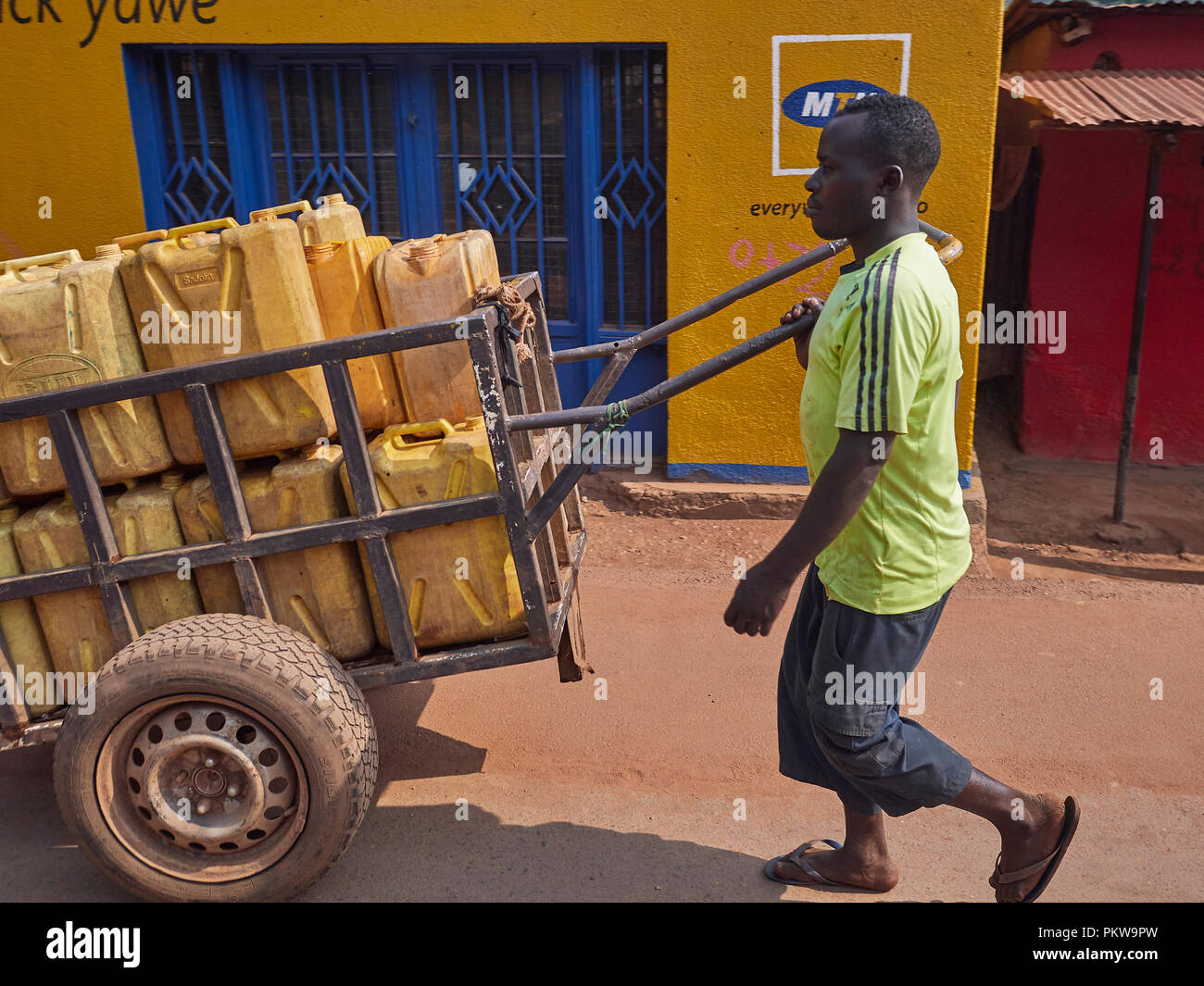 tight cropped man and his water cart passing a yellow and blue shop Stock Photo