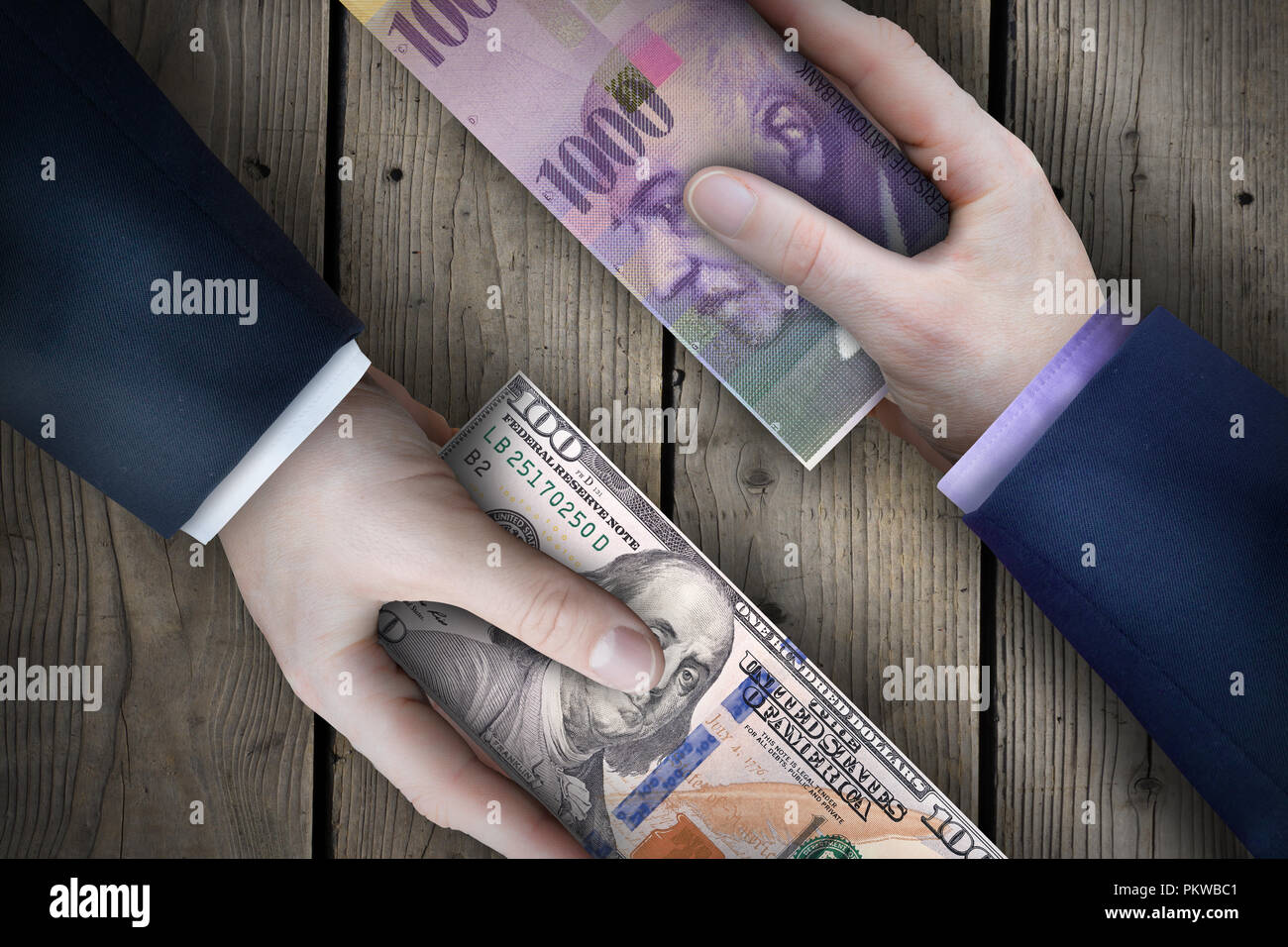 Two fiat currency bills being exchanged by two business people as part of a business transaction. Stock Photo