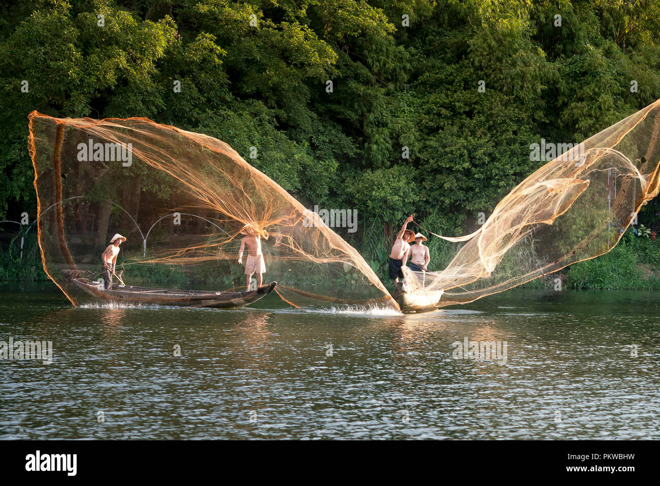 Fishermen are throwing fishing nets into the river in the sunset in Hue  city, Vietnam Stock Photo - Alamy