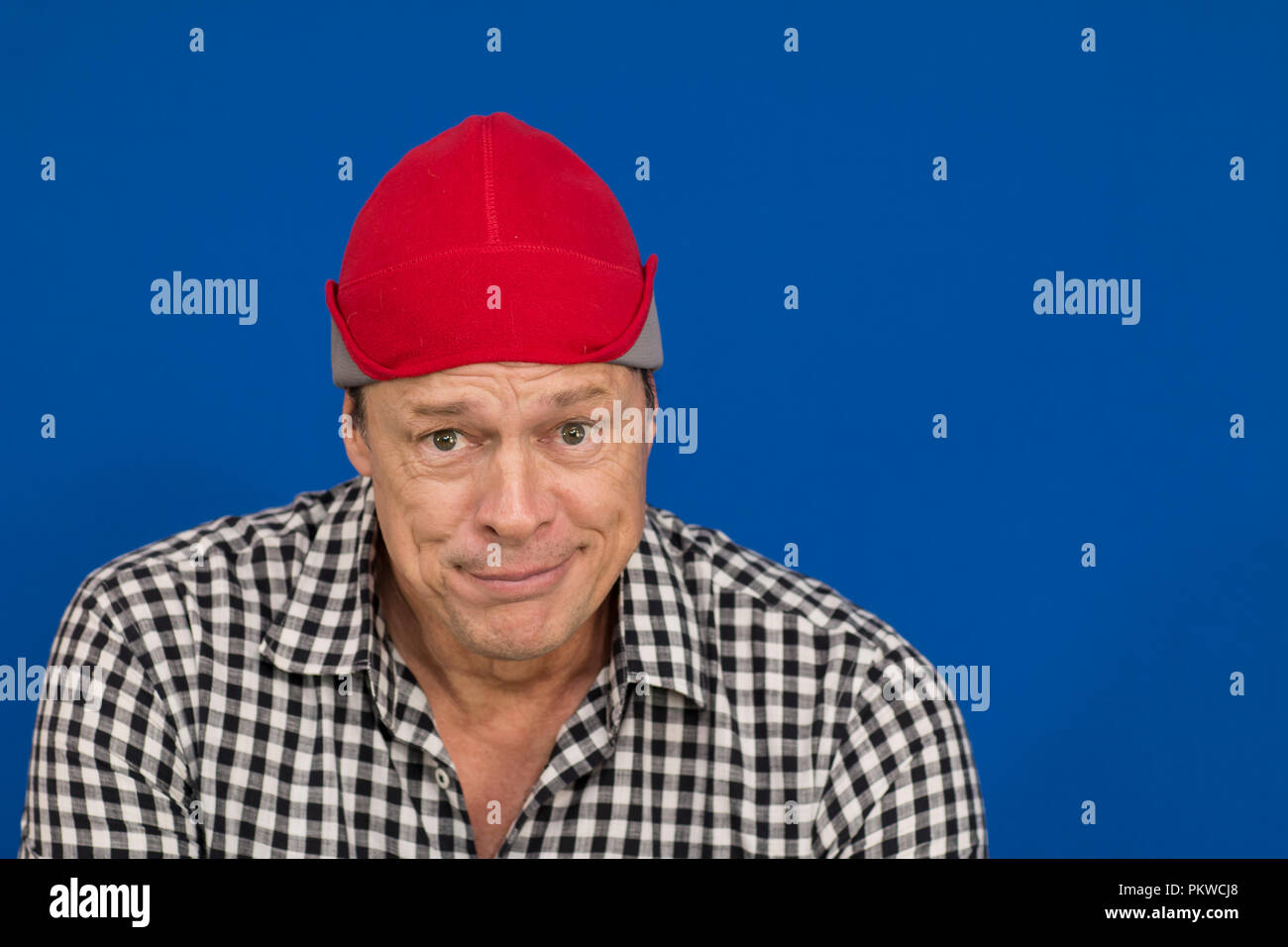 Man with red hat and plaid shirt, black and white and one half smile on his face Stock Photo