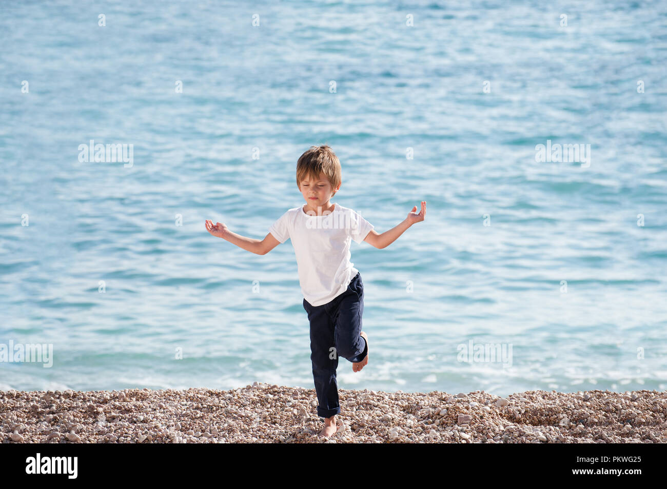 healthy little child practice yoga on sea shore in autumn spring season Stock Photo