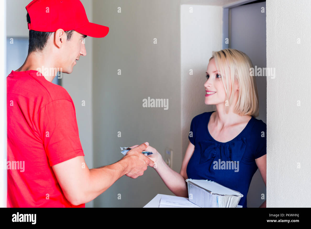 Delivery man taking payment from female customer Stock Photo - Alamy