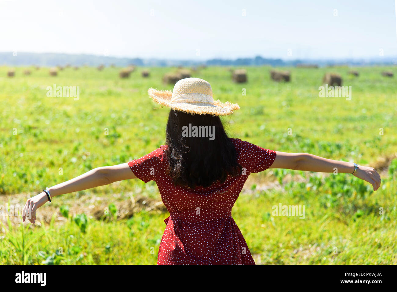 Girl wearing red dress in a harvested wheat field Stock Photo