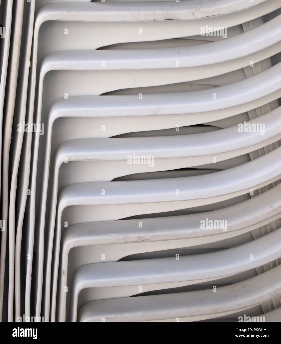 White plastic chairs stacked, showing interesting pattern Stock Photo