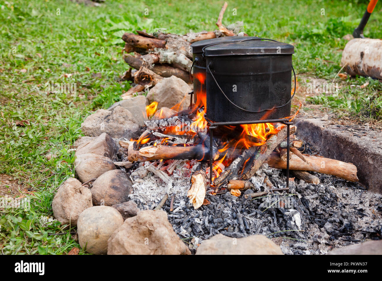 Cooking meal in kettles on burning campfire at wild camping Stock Photo