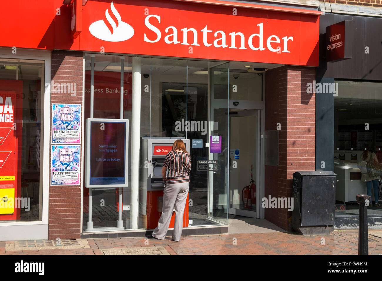 Santander bank with a woman at a cash point, ashford high street, kent, uk Stock Photo