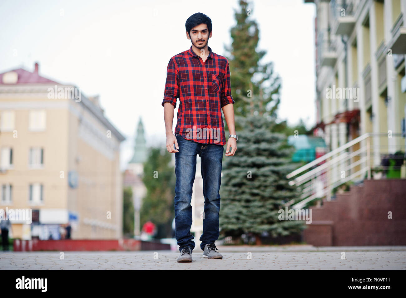 Young indian student man at red checkered shirt and jeans posed at city  Stock Photo - Alamy