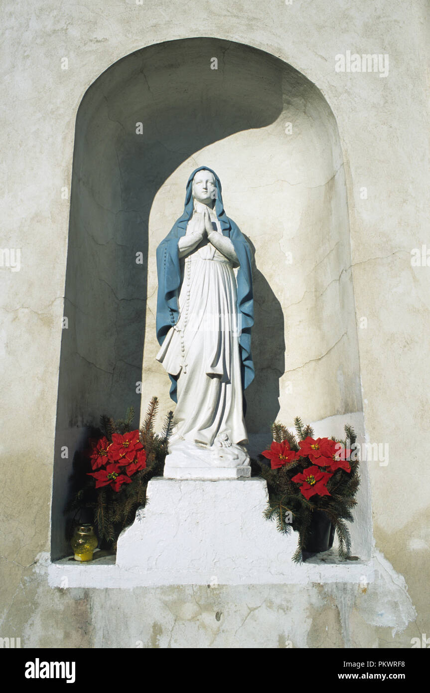 Small shrine of the Virgin Mary set into a wall outside a church in Klodawa, Poland. Stock Photo